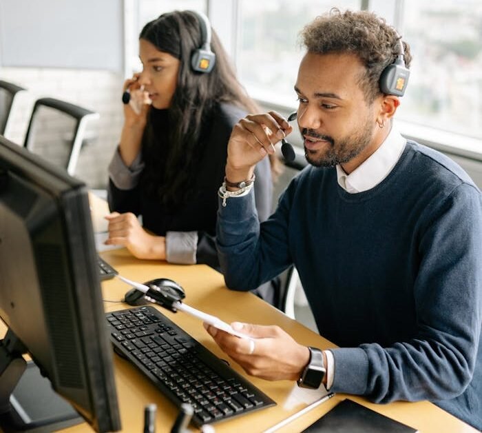 Man and Woman Wearing Headphones while Working in the Office